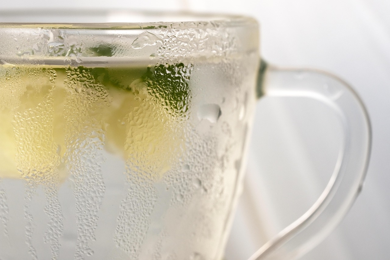 Tazza di acqua calda con limone su un tavolo, simbolo di benessere e salute mattutina.