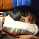 Persona che dorme su un letto, circondata da elementi scientifici e dati sul sonno e il peso.