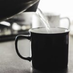 Uomo che sorseggia acqua calda al mattino, illustrando i benefici per la salute dopo 30 giorni.