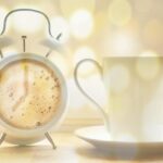 Una tazza di caffè su un tavolo, con un orologio che segna il momento ideale per berlo.