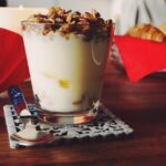 Immagine di un vasetto di yogurt con frutta fresca, simbolo di un'alimentazione sana per glicemia e colesterolo.