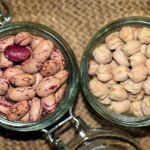 Legumi secchi cotti in pentola, con fumi di vapore e ingredienti freschi intorno.