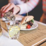 Immagine di un bicchiere d'acqua con un misuratore di pressione accanto, simbolo di idratazione e salute.