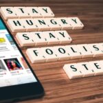 Persona che usa uno smartphone a letto, visibilmente preoccupata per le notizie negative.